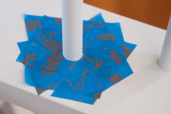 Pieces of blue paper or tape surround a white pole.