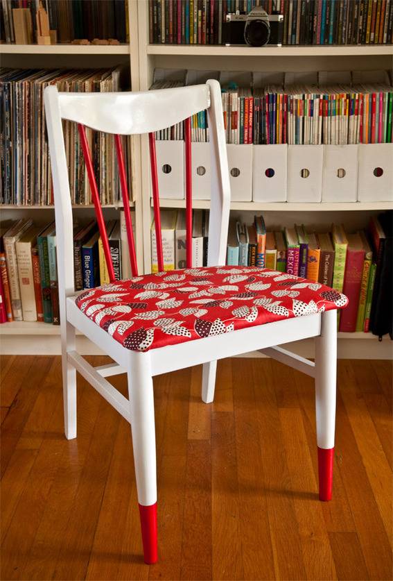 A red and white chair is in front of a large white bookcase.