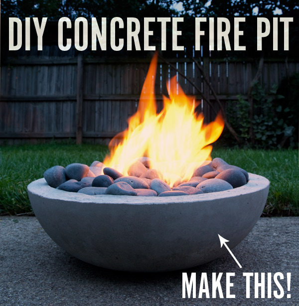 A concrete fire pit contains rounded stones and a fire.