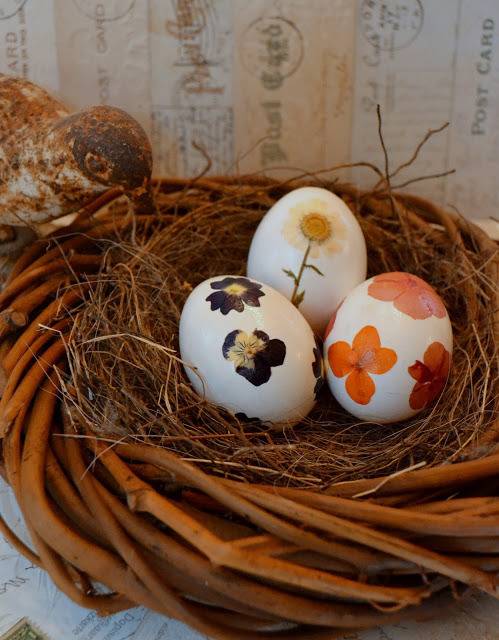 Three painted eggs are sitting in a bird's nest.