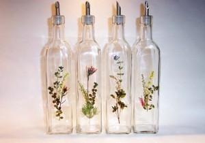 Flowers are arranged in four different glass bottles.