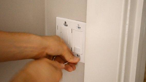 A pair of light switches being installed with a tool.