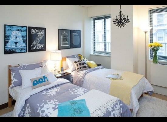 Two beds are side by side in a bedroom with matching wall art and a matching chandelier.