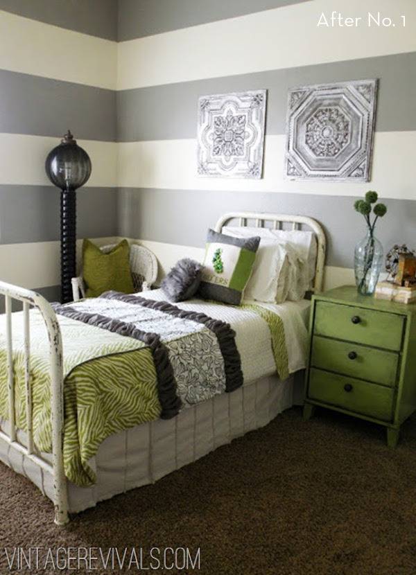 A bed with a green and white sheet has gray and white striped walls.