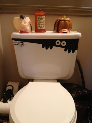 A toilet with a monster painted on the top.