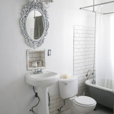 A mirror above a white sink and toilet in a bathroom with a tub.
