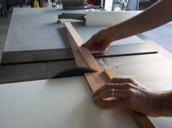 A man is cutting thin strips of wood on a tablesaw.