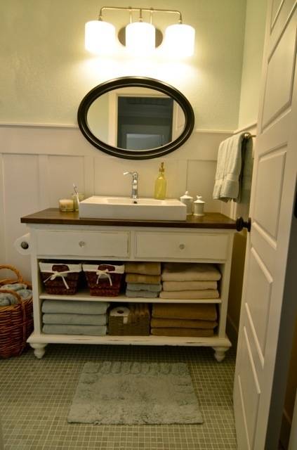 Bathroom counter with towels folded underneath beneath an oval mirror in a bathroom.