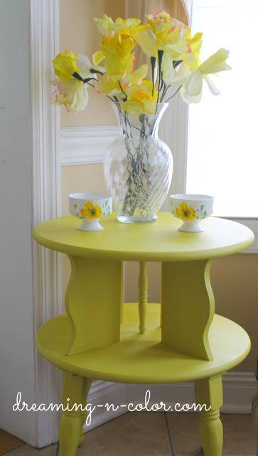 "An End Table decorated with Yellow Stools and Yellow Flowers"