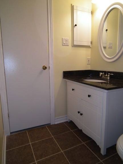A white bathroom has a black sink countertop.