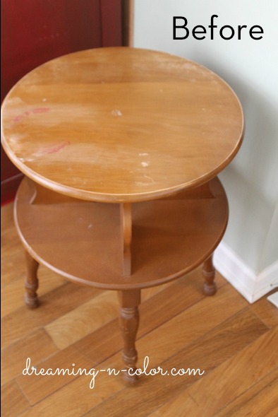 A two layered wooden table is sitting near a white wall.