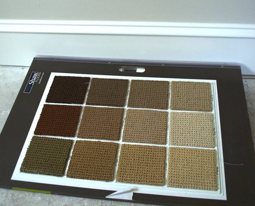 Square carpet samples on a board on the floor.