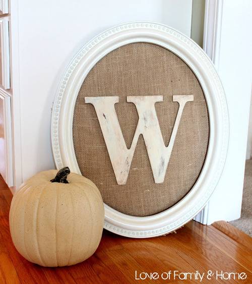 The letter W inside an oval frame near a pale pumpkin.