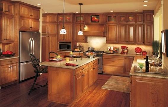 Chairs sit at an island in a kitchen with wooden cabinets and counters.