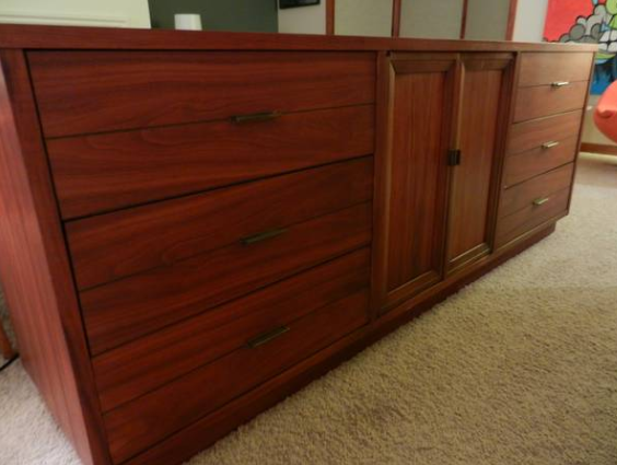 A huge, long dresser is dark wooden brown.