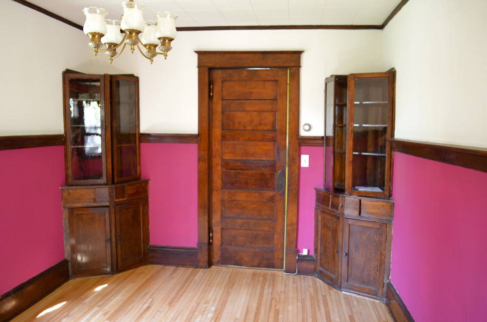 A bare room with two wood cabinets and a door.