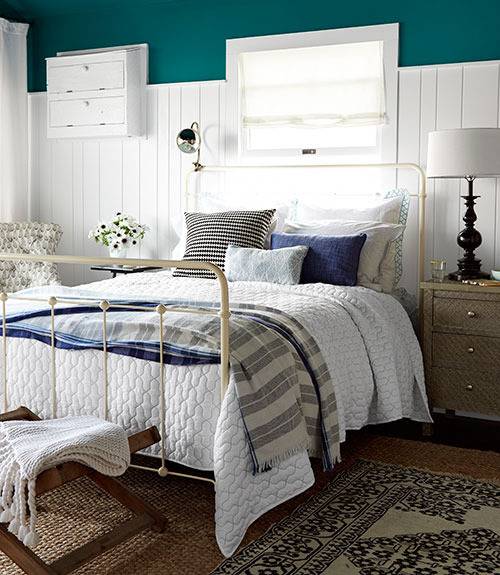 A bedroom has a white metal frame on a bed with white covers and teal walls.