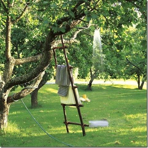 A flimsy ladder holding towels leans against a tree.