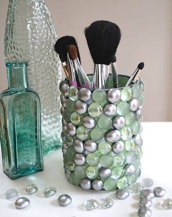 Several make up brushes are in a pearly blue cup.