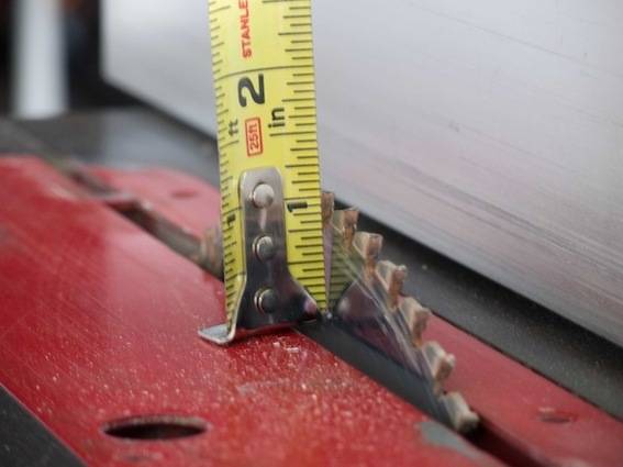 A tape measurer is standing on the end of a saw blade.