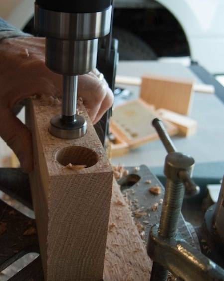 A man cuts holes in a piece of wood with a saw.