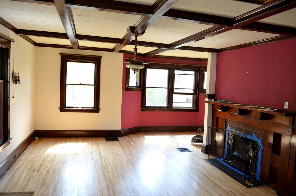 An empty wooden floored room with red and white wall and a fire place.
