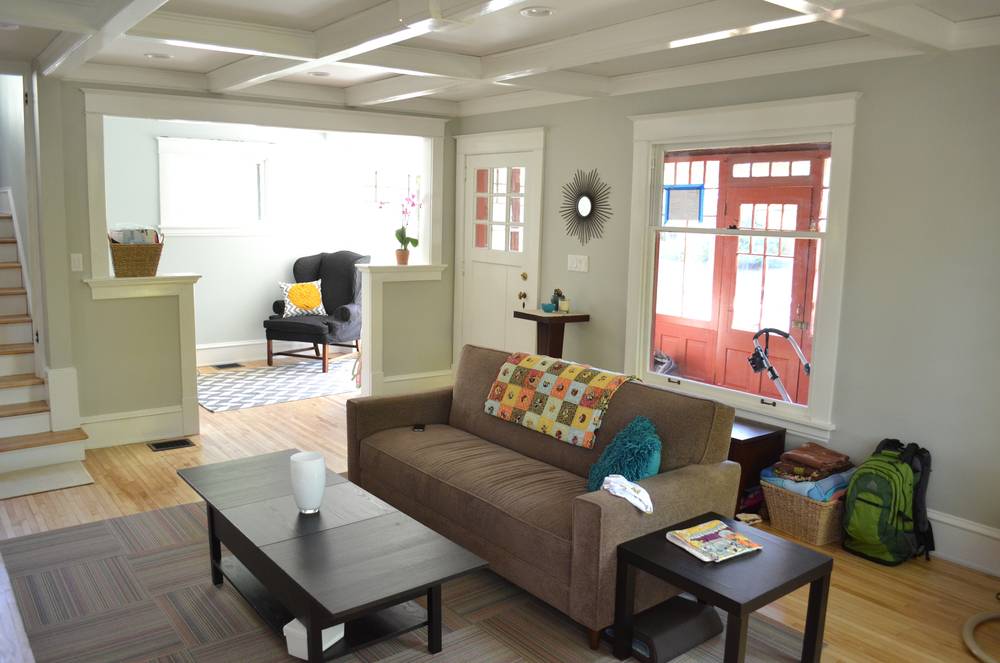 Sofa with pillow and blanket next to coffee and end tables in a living room.