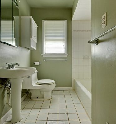 Ceramic toilet and sink in a white tiled bathroom.