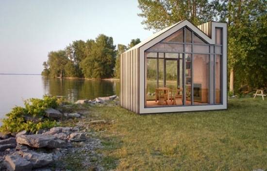 A small building with two glass sides sits next to a lake.