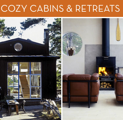 A dark cabin with a large glass front and a wooden stairway inside, two leather chairs in front of an antique fireplace and a oar on the wall.