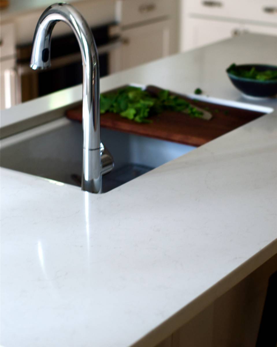 A sink basin sits in a light colored counter.