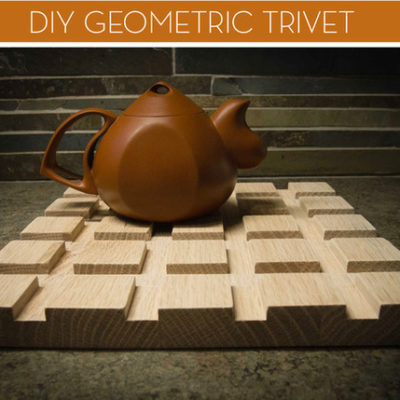 Teapot on a wood trivet with a geometric design.