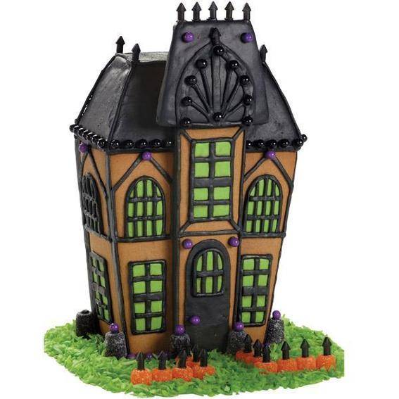 A gingerbread spooky house with a black roof and a face on the attic, green windows and grass around the bottom.