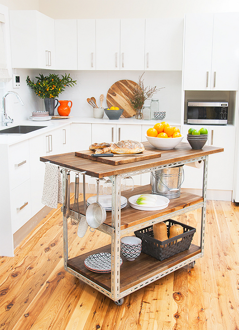 A kitchen trolley with food on it is in a kitchen with white counters and cabinets.