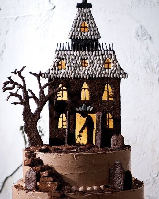 A multi tiered cake looks like a dirt hill with a spooky house on top.