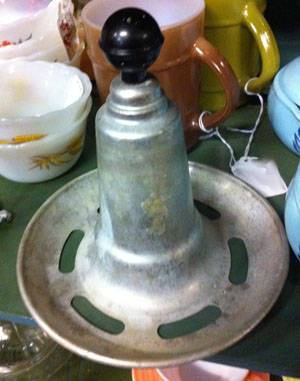 A vintage kitchen gadget with a base that has slots in it and a black bulb on top of a cone.