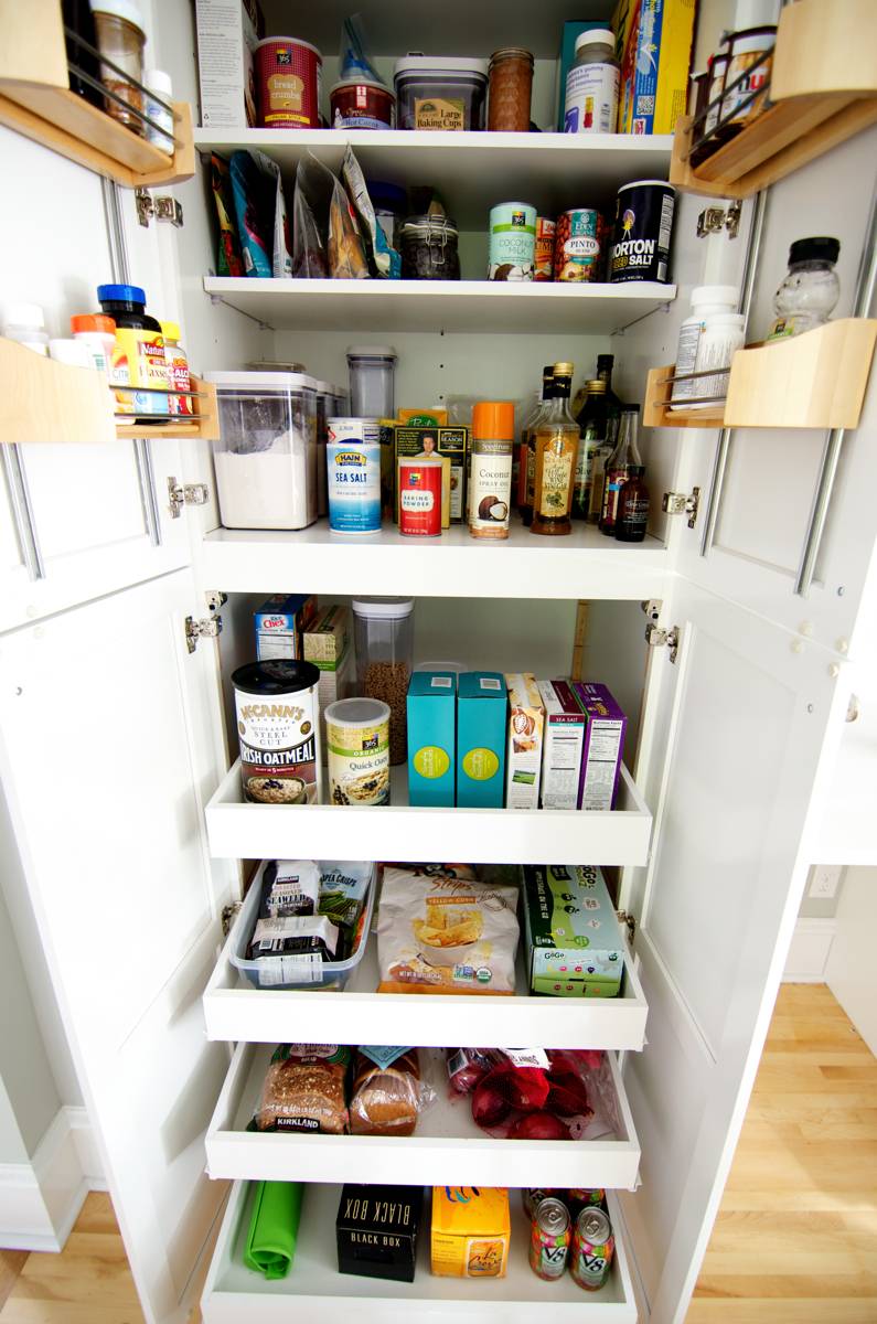 Jars of spices in pantry shelf with roll-out drawers.