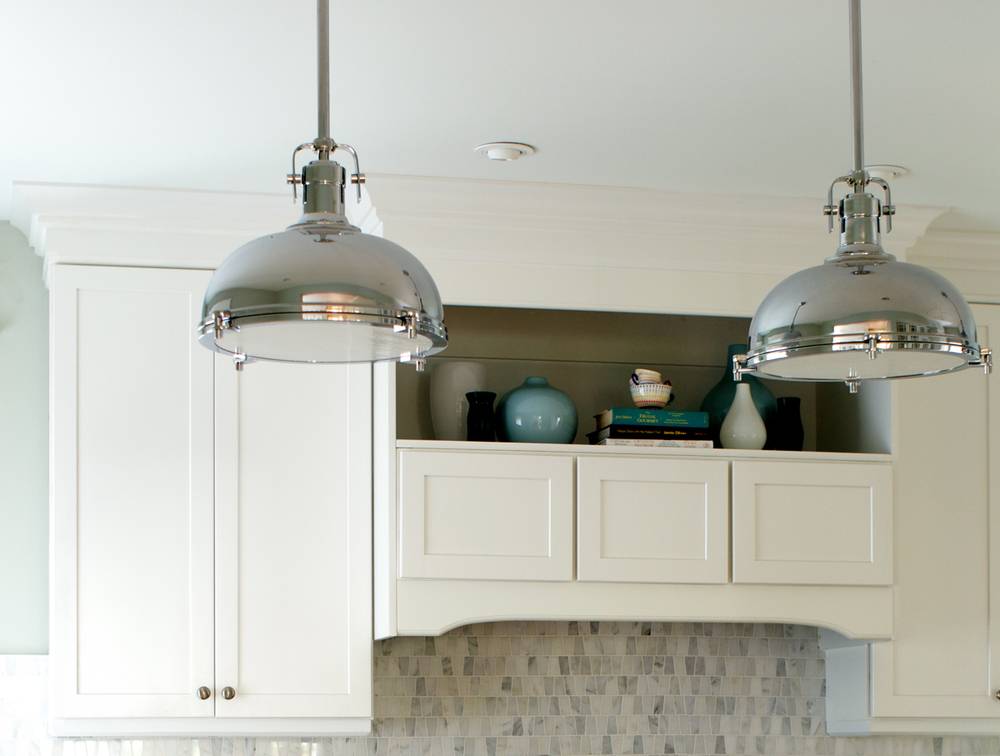 Two silver dome shaped lights hanging from a kitchen ceiling.