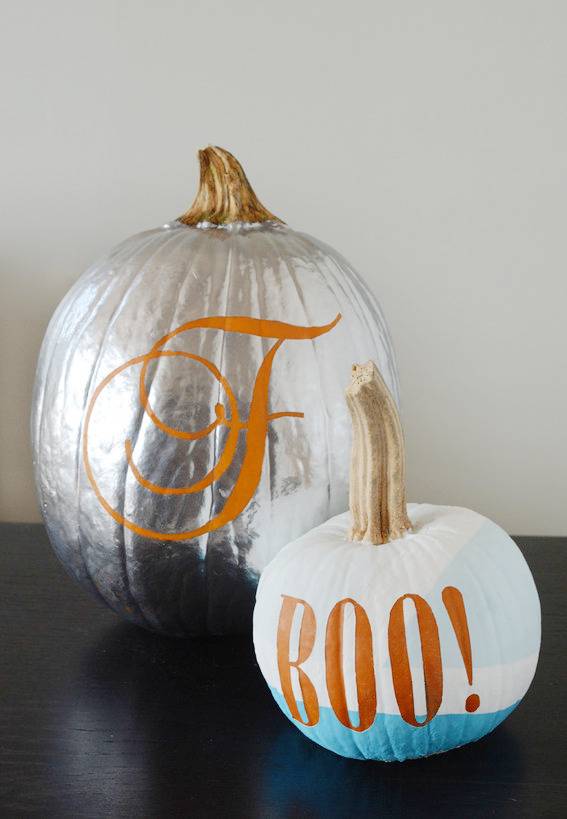 Silver painted pumpkin with cursive letter F next to Boo! painted pumpkin.