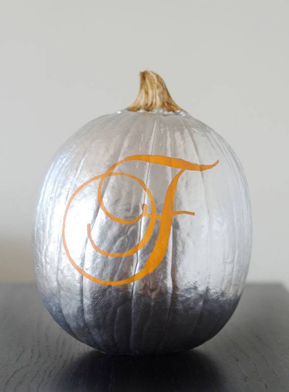 A pumpkin that has been spray painted bright silver and has an f on it.