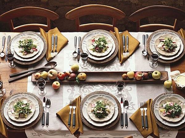 A table setting for six with gold napkins and apples in the centerpiece.