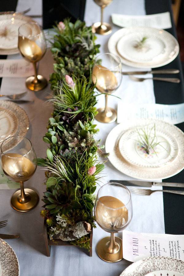 Gold and clear wine glasses sit near place settings at a holiday dinner table