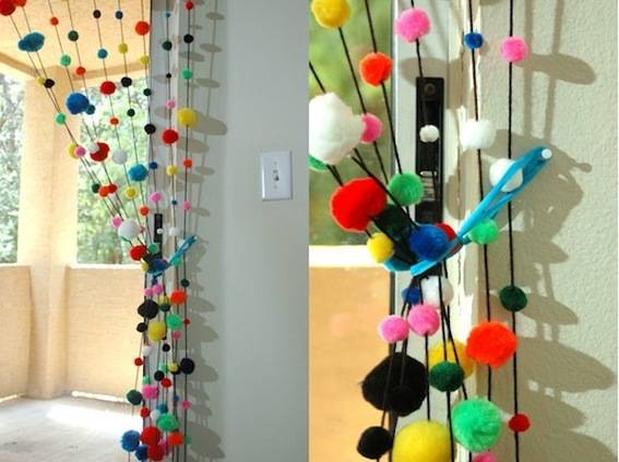 Pom poms on strings in a curtain for a room divider.