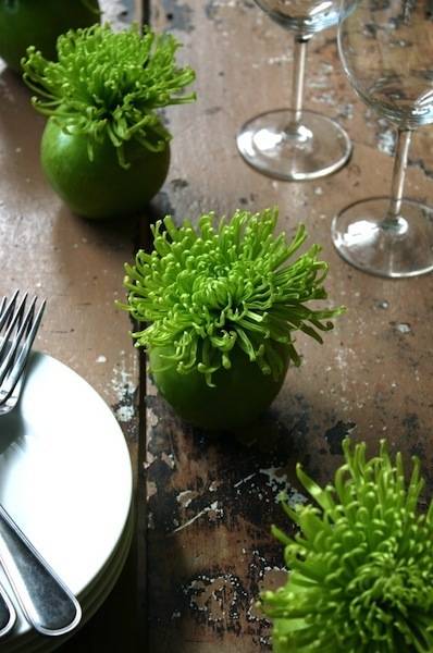 Four bright green plants in for bright green round planters on a table with place settings