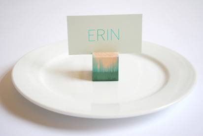A round, white plate has a green and orange colored block on it with the name of Erin balanced on it.