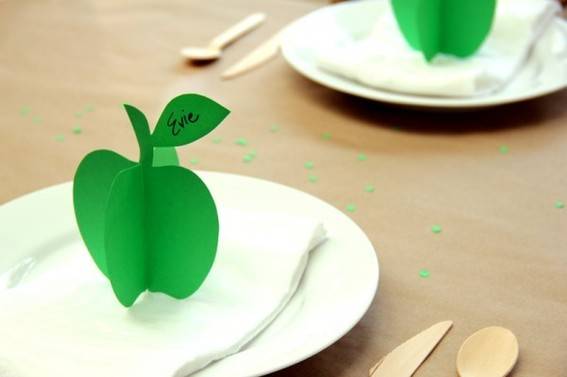 Paper green apples sit on white plates.