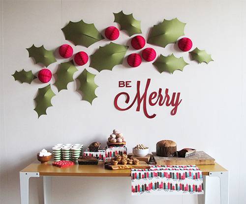 Wall decorated with paper leafs, cherries and table with food items.