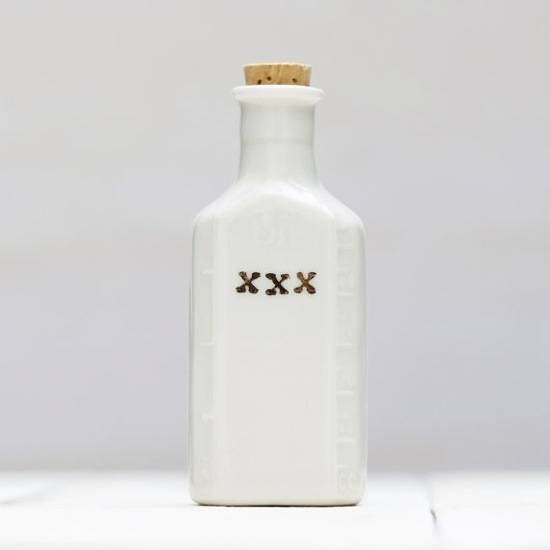 A white porcelain toiletry bottle with a cork in it.