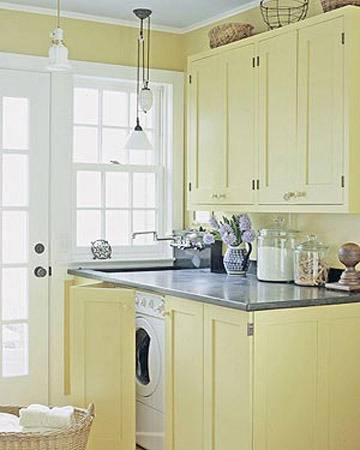 Kitchen with pastel yellow counters, and a washing machine in the island of the kitchen.
