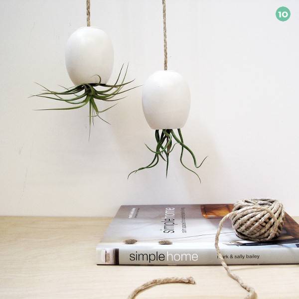 Flowers are growing upside down in white hanging planters.